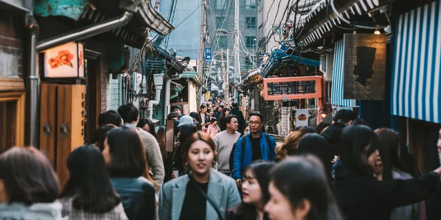 people walking between korean houses